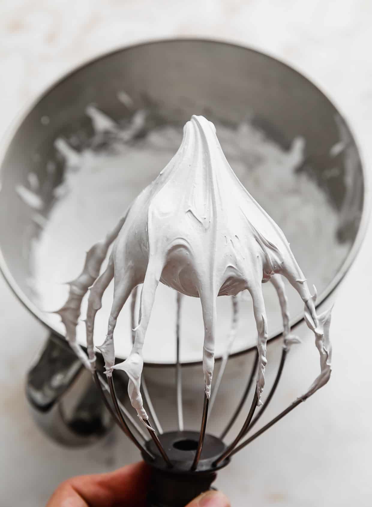A whisk with marshmallow meringue frosting on it.