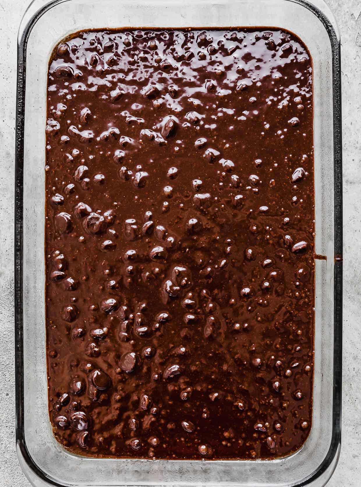 Raw brownie batter in a glass rectangular pan.