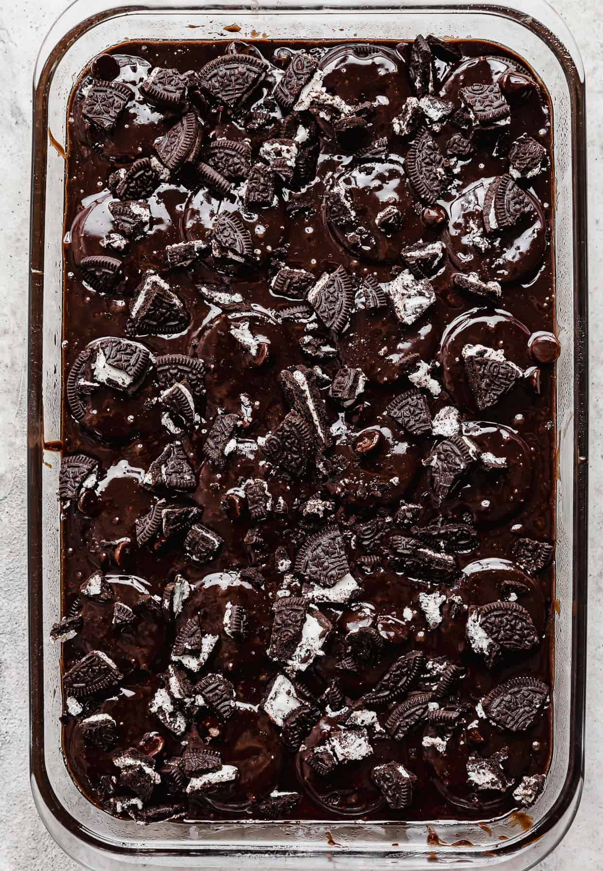 Chopped oreos sprinkled overtop brownie batter in a rectangle pan.