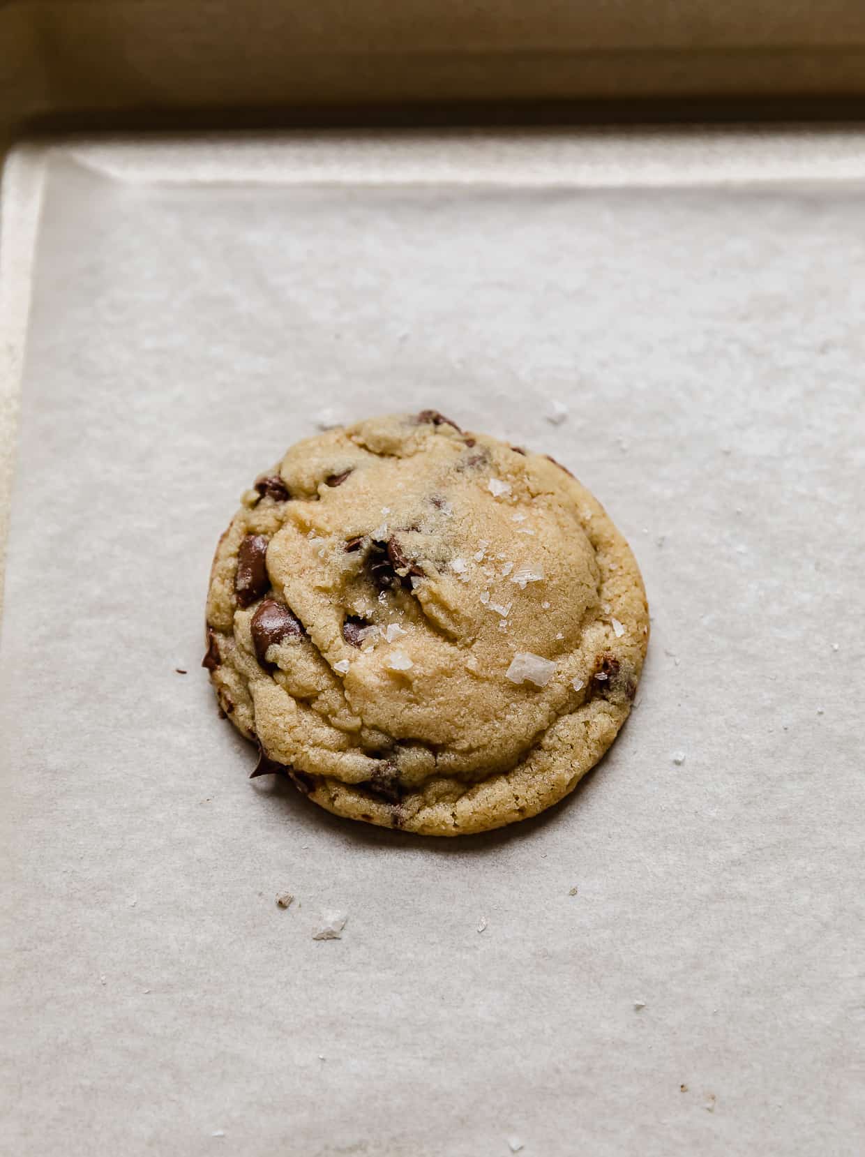 A Small Batch Chocolate Chip Cookie topped with sea salt on a baking sheet.