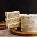 A three layered Brown Butter Cake with a slice of cake cut and balancing on a knife.