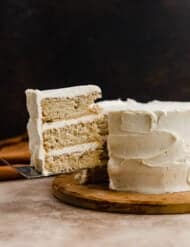 A three layered Brown Butter Cake with a slice of cake cut and balancing on a knife.