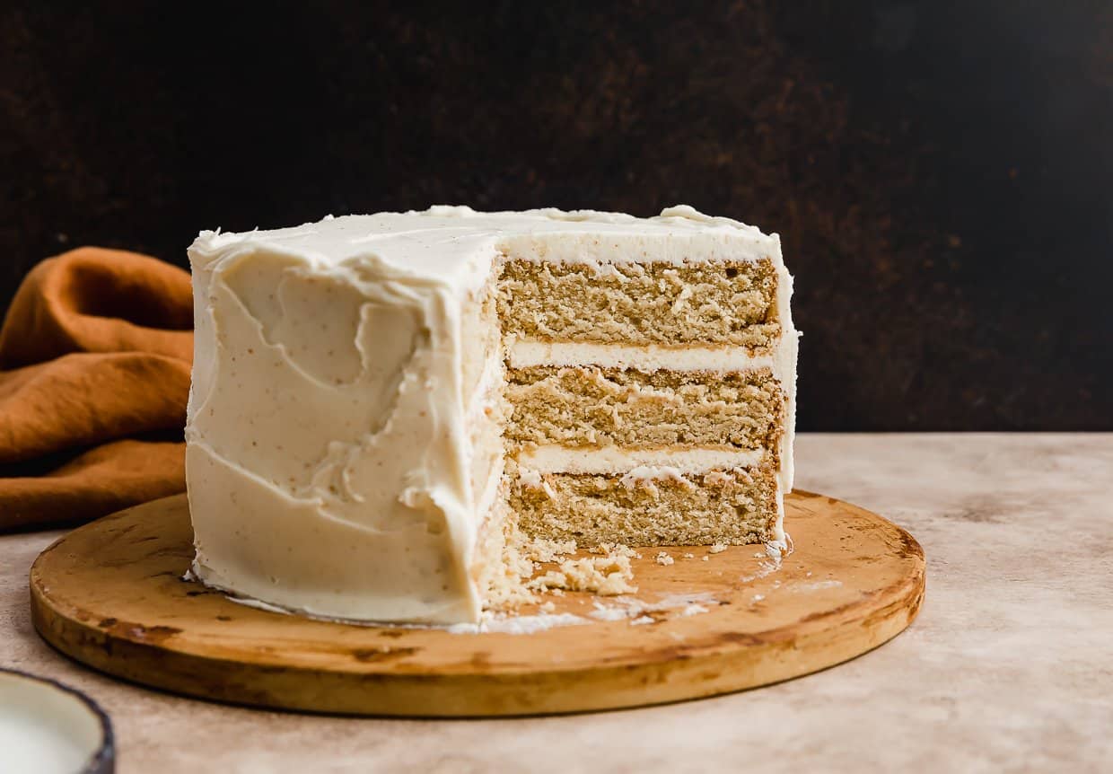 A three layered brown butter cake recipe with a slice removed from the cake.