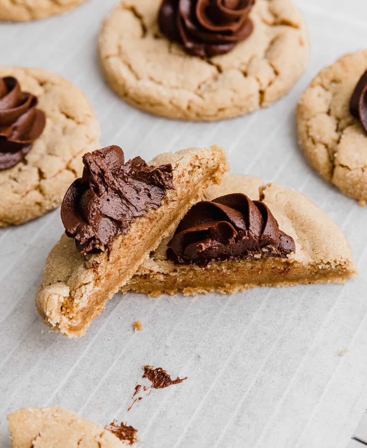 A Crumbl Peanut Butter Blossom Cookie cut int half on a white parchment paper. 