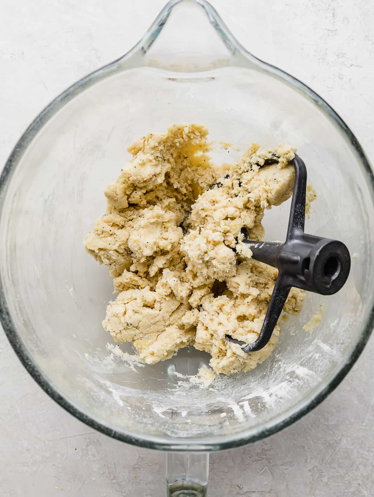 Lemon Poppy Seed Cookie dough in a glass bowl on a white background.