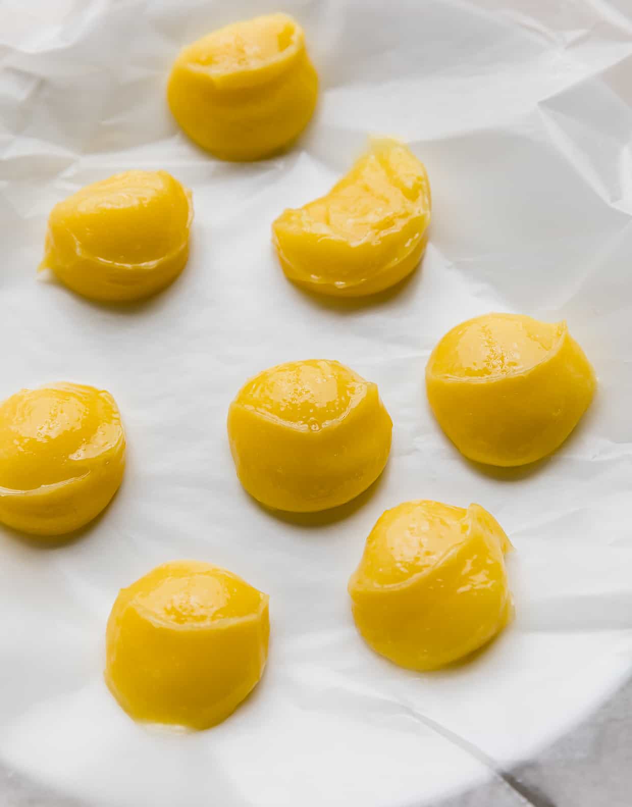 Lemon curd dollops on a wax paper lined white plate.