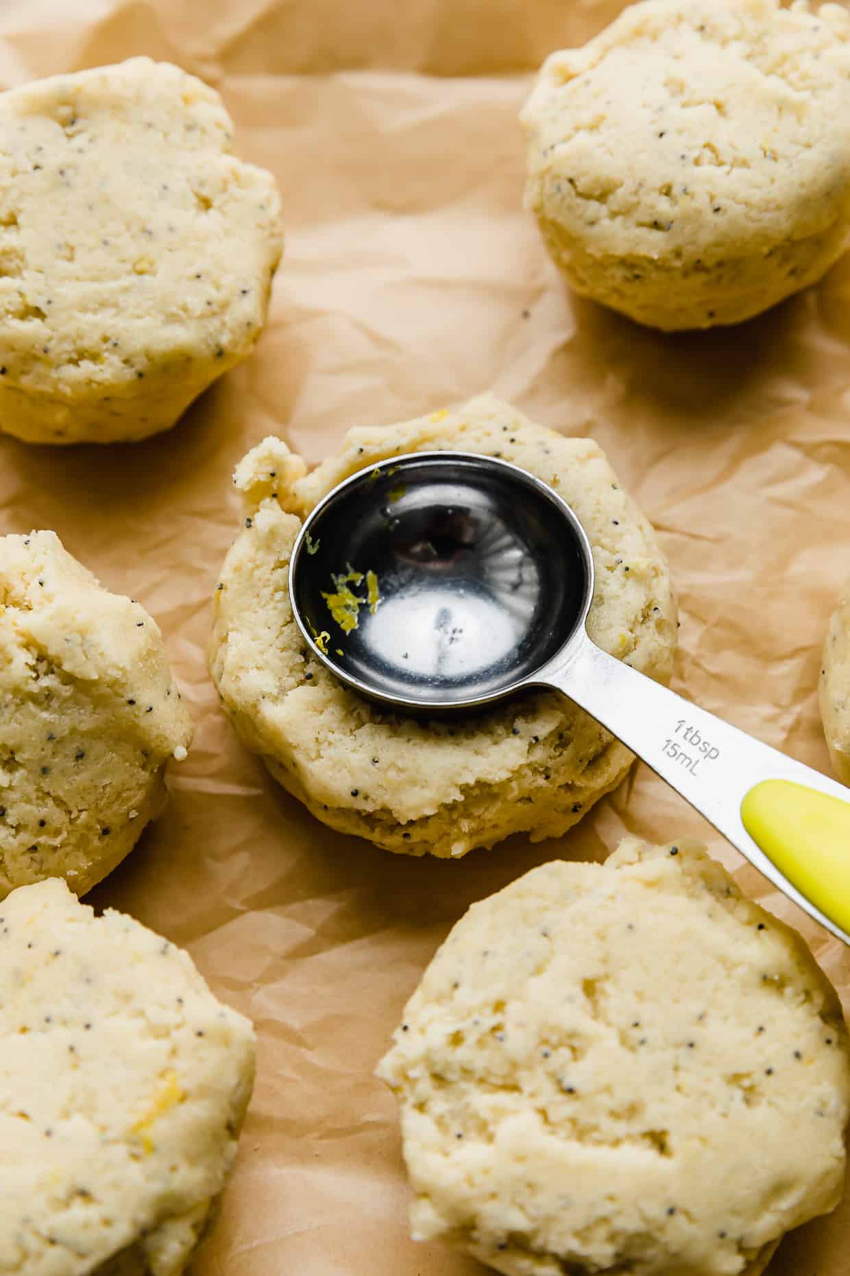 A tablespoon pressing into lemon poppy seed cookie dough.
