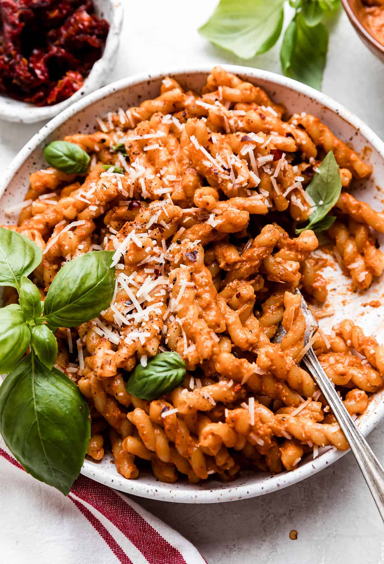 Red Pesto Pasta on a white plate with a fork scooping up noodles.