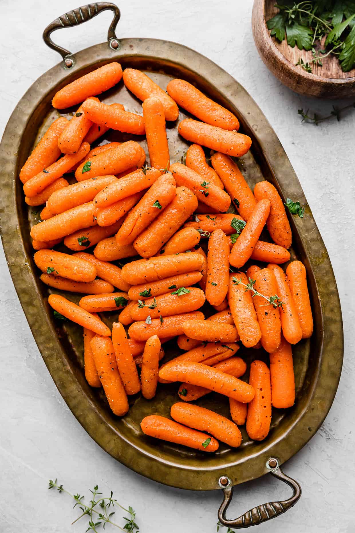 Roasted Baby Carrots on a bronze oval plate on a white background.