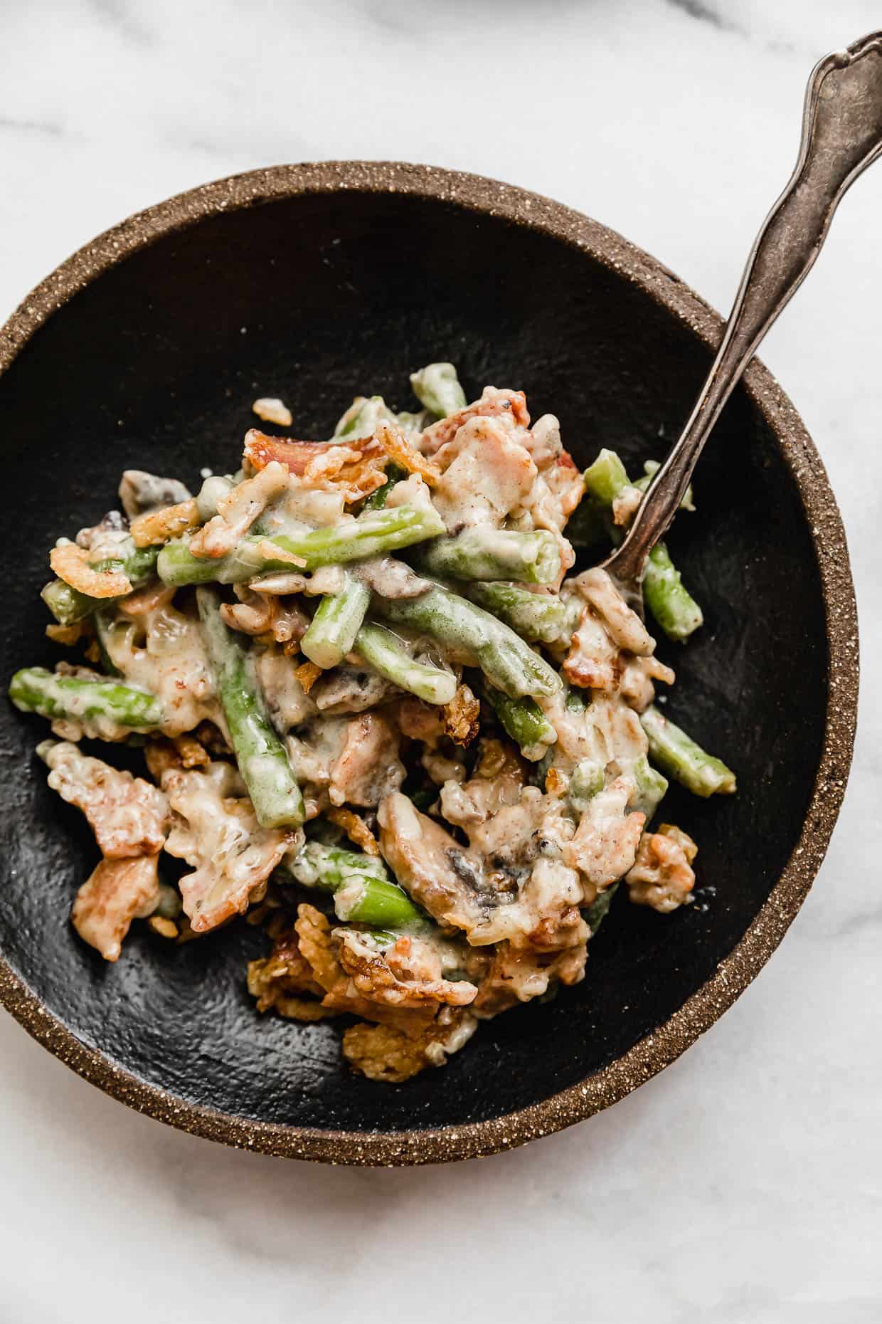 Bacon Green Bean Casserole on a black plate on a white background.