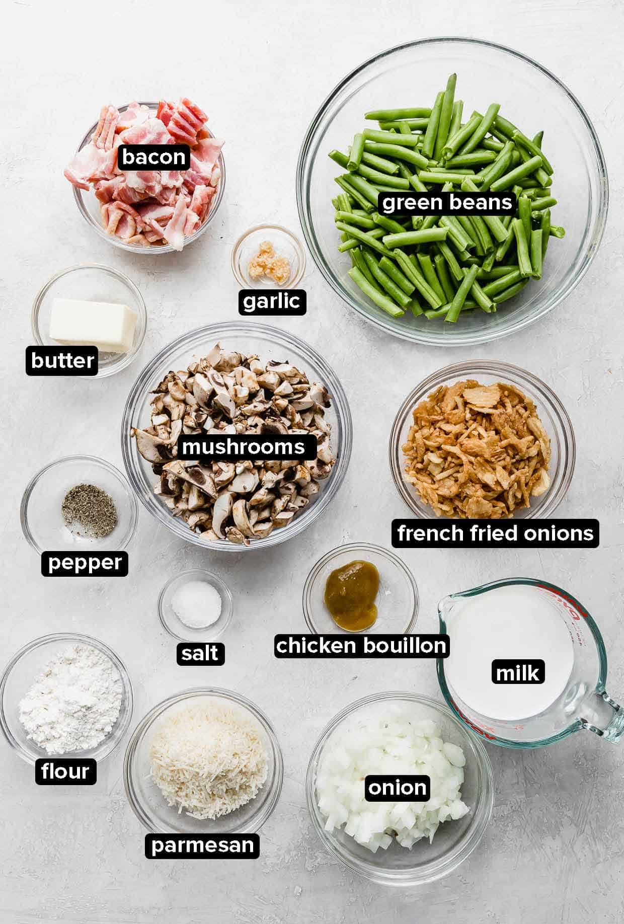 Bacon Green Bean Casserole ingredients portioned into glass bowls on a white background.