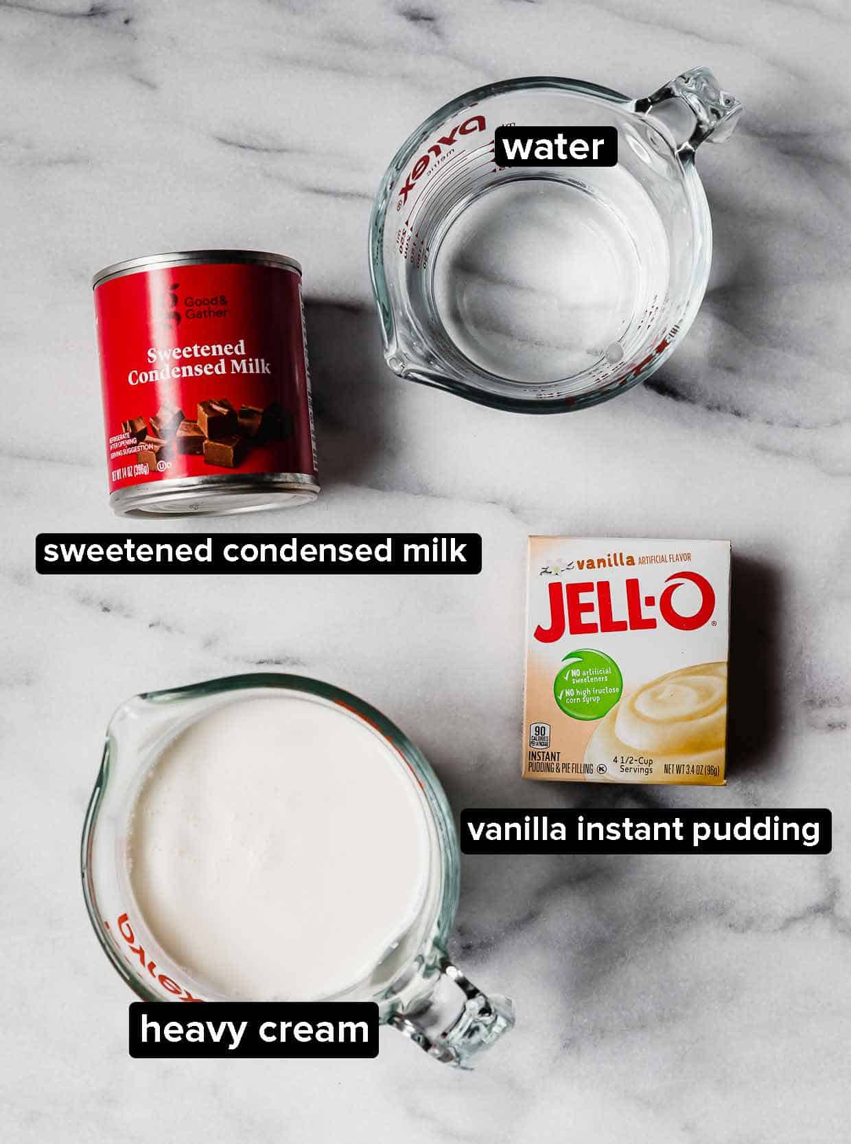 Sweetened condensed milk, heavy cream, water, and vanilla pudding on a marble background.
