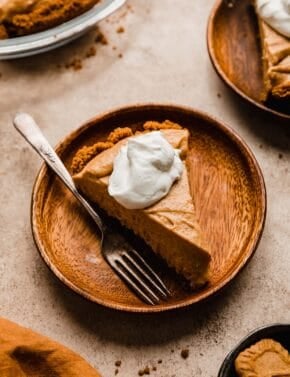A slice of a Biscoff Pumpkin Pie on a wood plate.