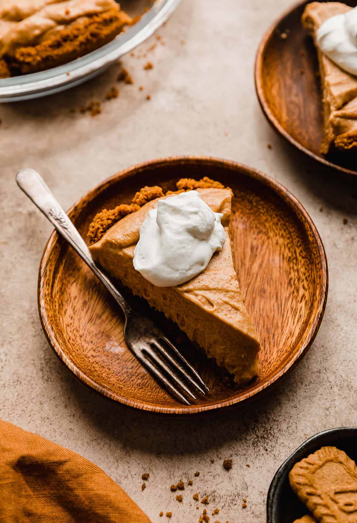 A slice of a Biscoff Pumpkin Pie on a wood plate.