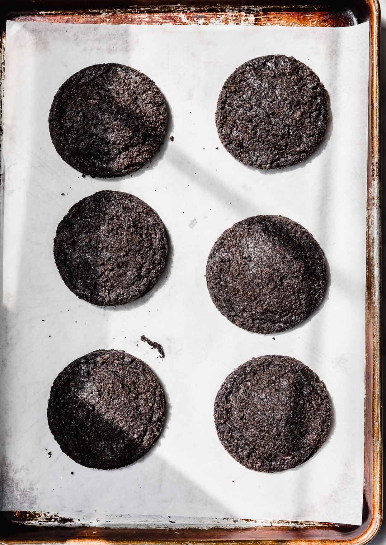 Six baked Dirt Cake Cookies on a parchment lined baking sheet.