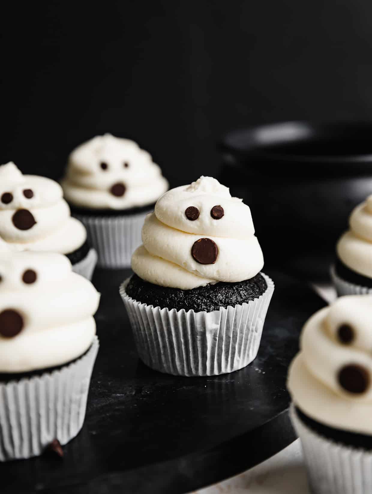 Ghost Cupcakes on a black table against a black background.