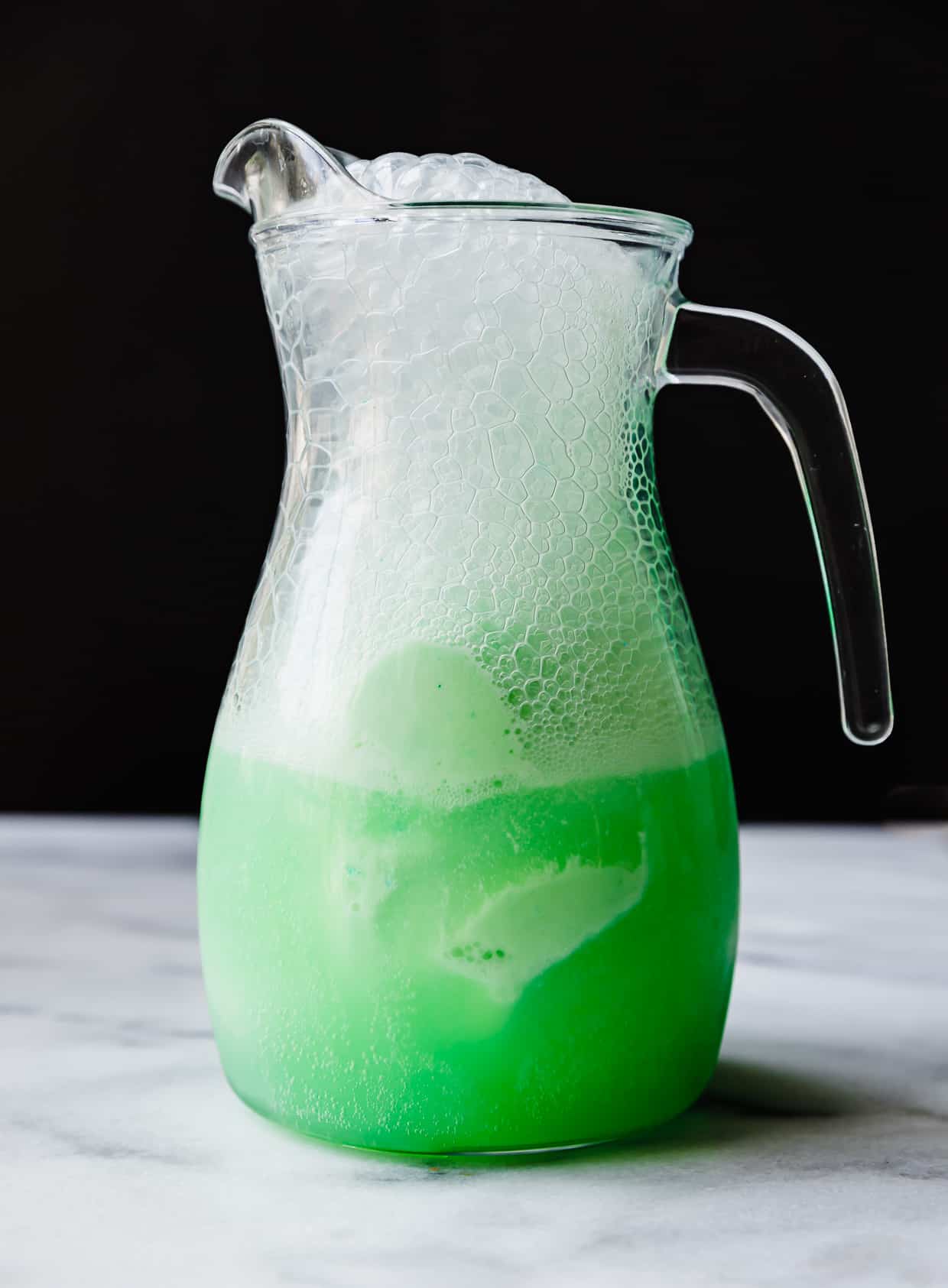 A glass pitcher filled with green Polyjuice Potion.