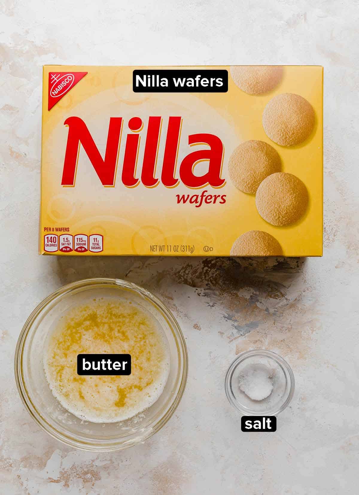 Nilla wafer box, melted butter, and salt on a white textured background.