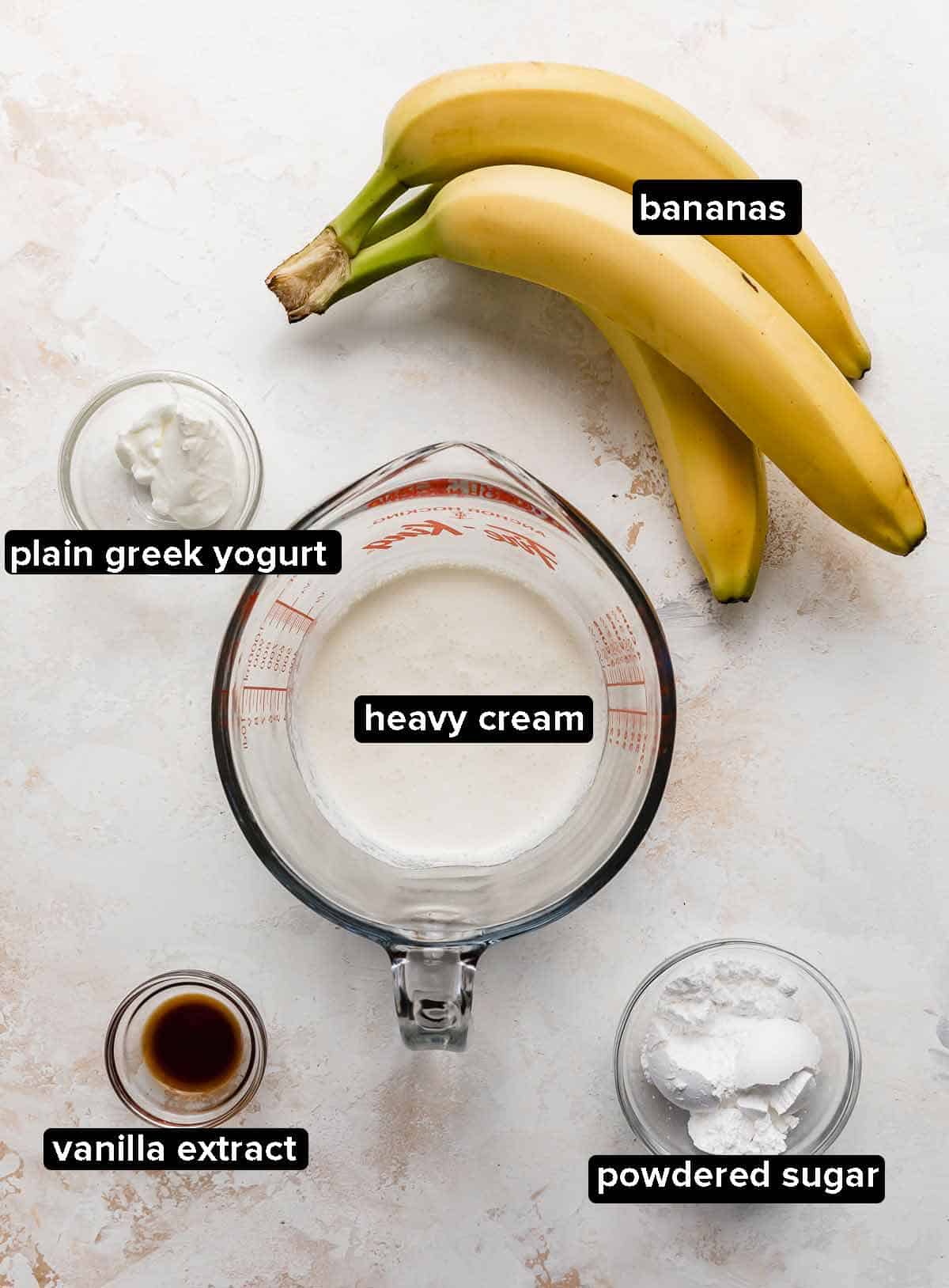 Banana cream pie toppings on a white background: heavy cream, bananas, vanilla, greek yogurt, and powdered sugar.