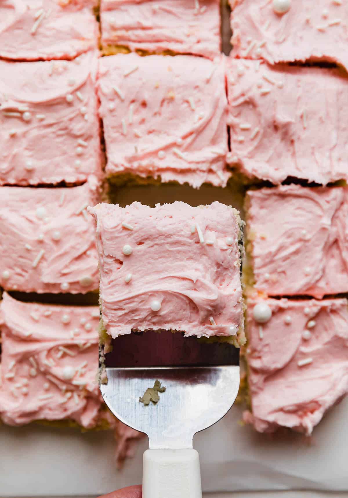 Cut sugar cookie bars topped with pink buttercream frosting.