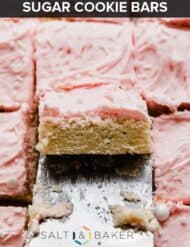 A metal spatula lifting up a square of pink frosting covered Sugar Cookie Bars.