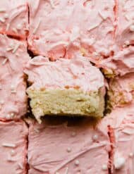 A Sugar Cookie Bar recipe cut into squares topped with pink frosting.