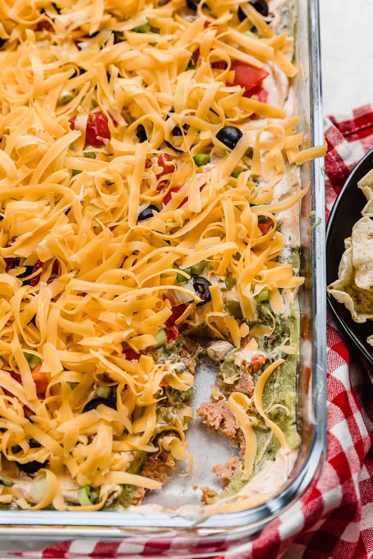 Cheese, tomato, olives, and onion topped Layered Taco Dip made with refried beans.