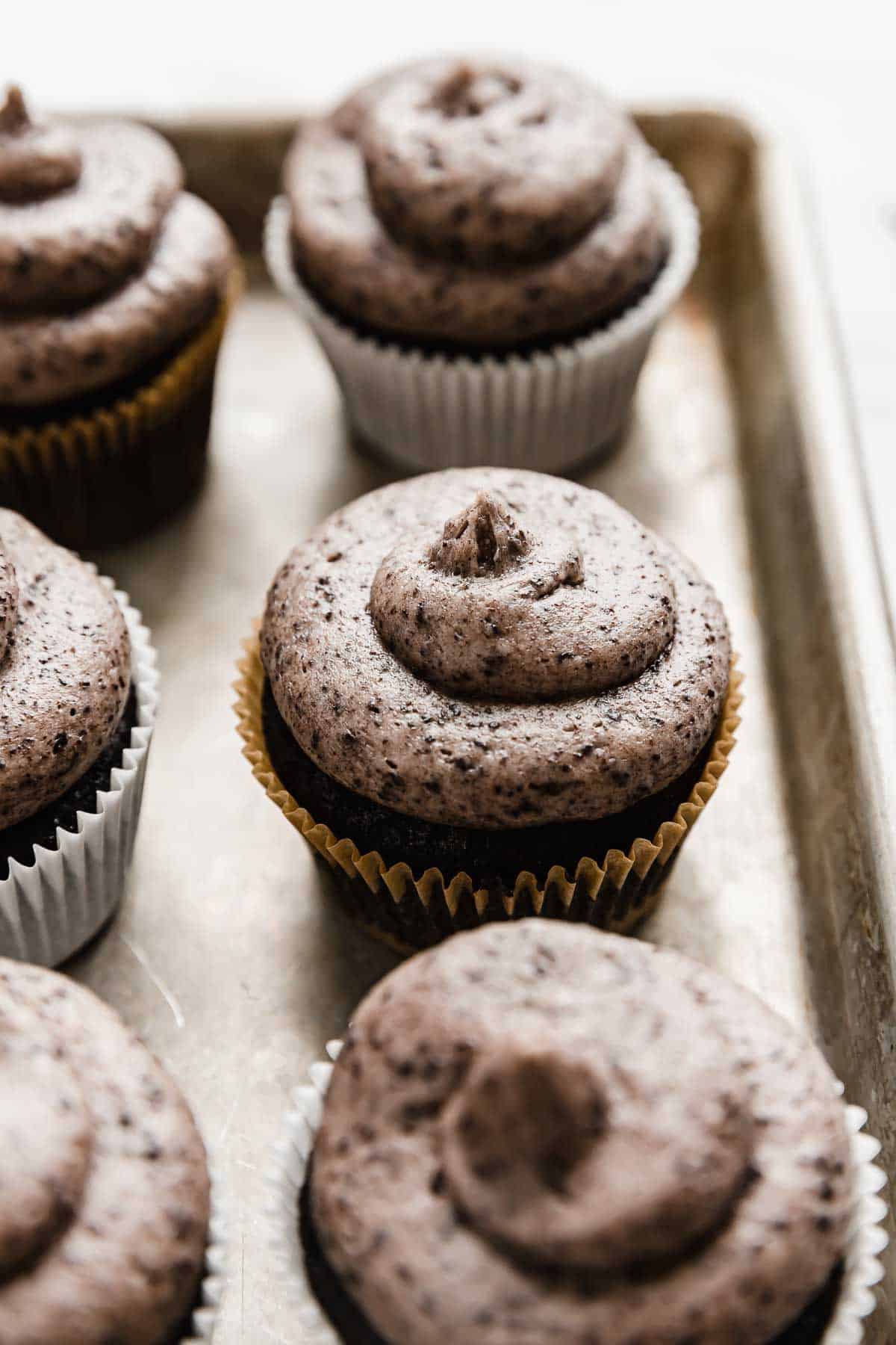 Oreo Cupcakes topped with a swirl of Oreo frosting, on a baking sheet.