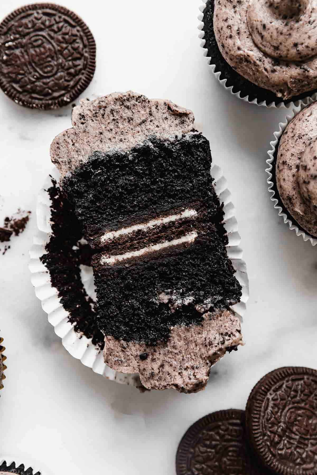 An oreo cupcake cut in half, showing that the Oreo cupcake was baked on a full Oreo cookie.