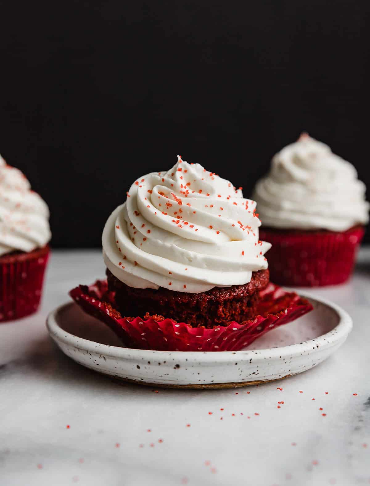 Red Velvet Cupcake on a white plate against a black background.