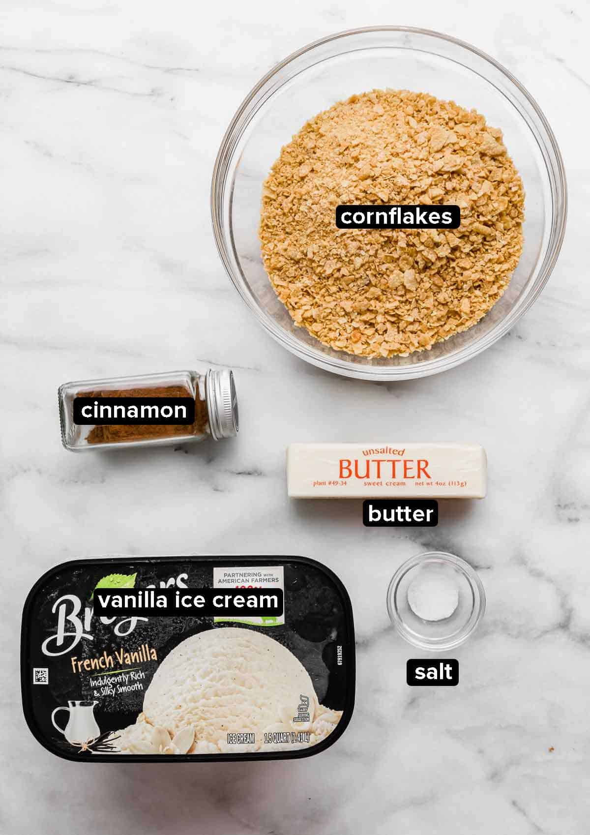 Fried ice cream ingredients on a white background: vanilla ice cream, cornflakes, cinnamon, butter, salt.