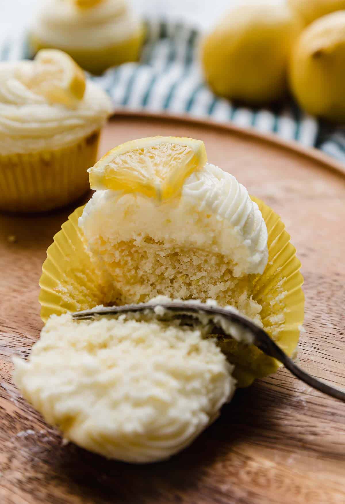 A fork cutting a lemon cupcake in half.