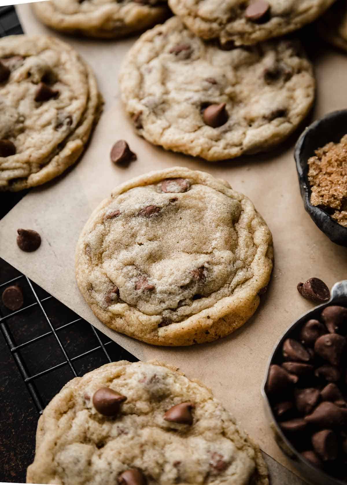 The best Milk Chocolate Chip Cookies on a Kraft colored parchment paper surrounded by milk chocolate chips.