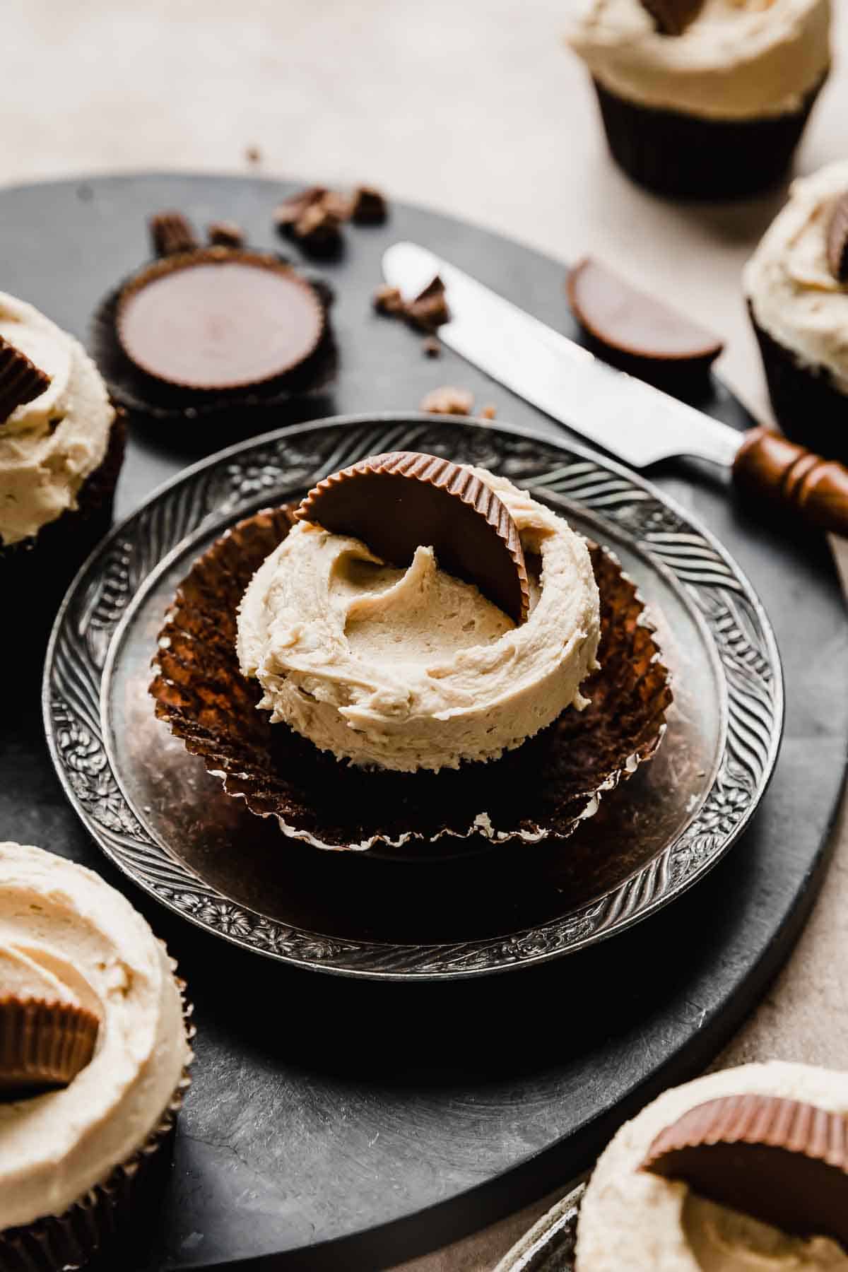 A Reeses Cupcake topped with peanut butter frosting and half of a Reese's peanut butter cup.