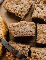 Banana Coffee Cake cut into squares with a yellowed banana next to the coffee cake.