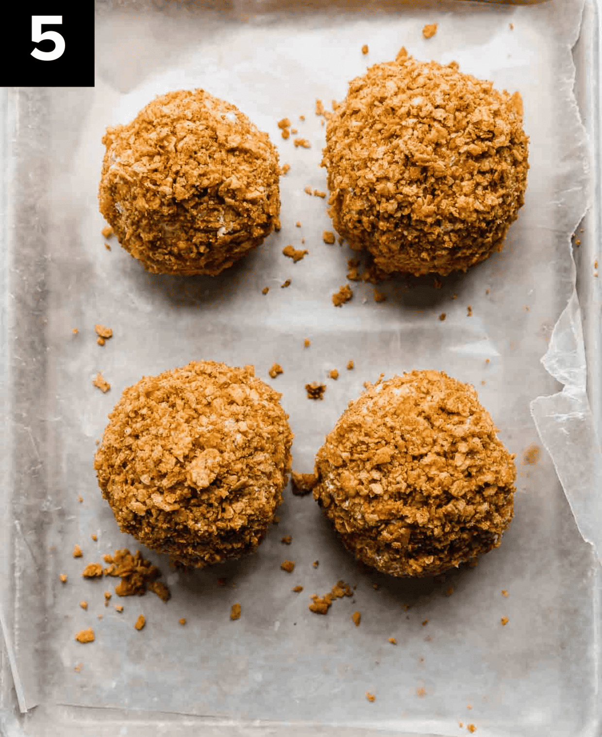 4 No fry Fried Ice Cream balls covered in crushed cornflake cereal on a baking sheet.