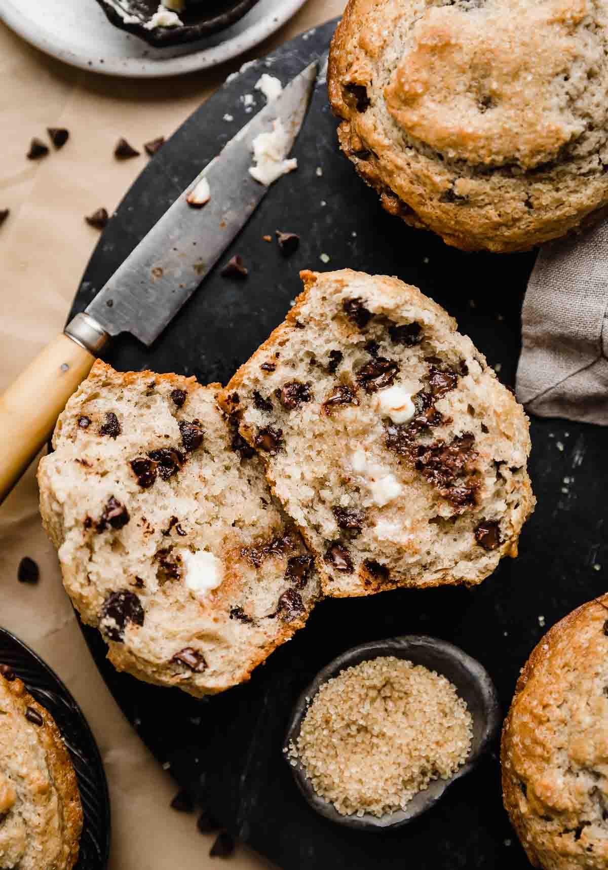 A Bakery Style Chocolate Chip Muffin cut in half with melted butter spread over each muffin half.