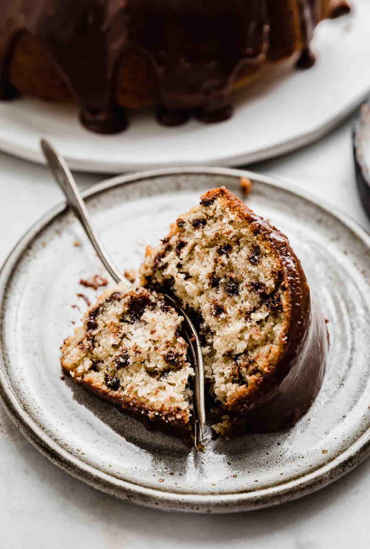 A slice of Chocolate Chip Bundt Cake on a gray plate with a fork cutting into the cake.