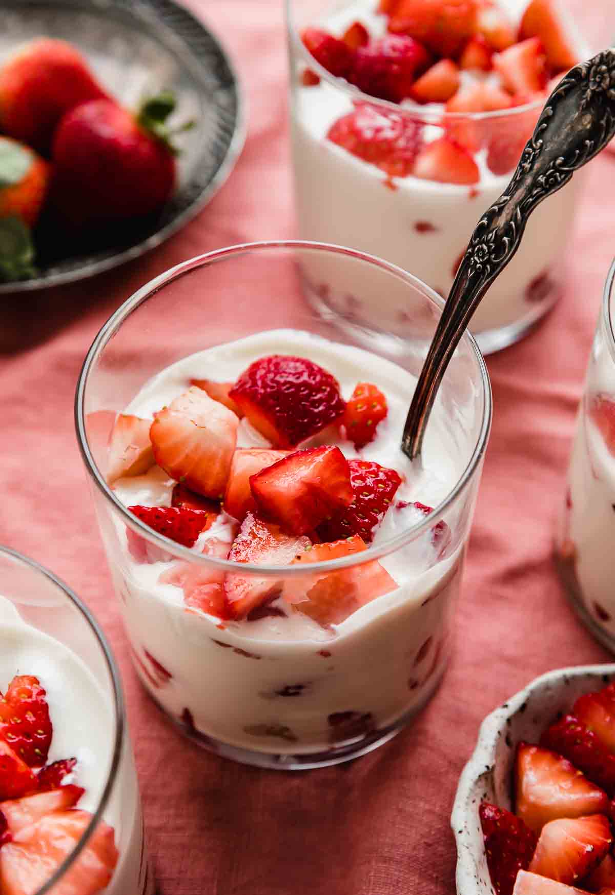 A glass cup filled with Strawberries and Cream (Fresas con Crema), on a light red linen napkin.