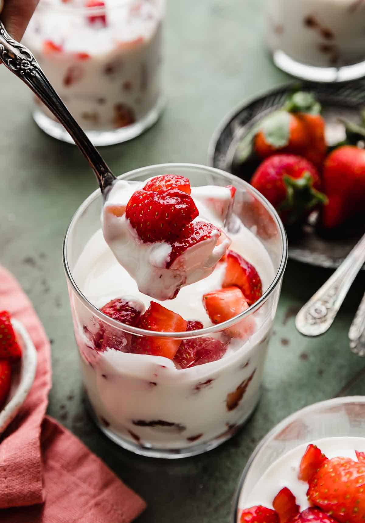 A spoon scooping up Strawberries and Cream (Fresas con Crema) from a glass cup.