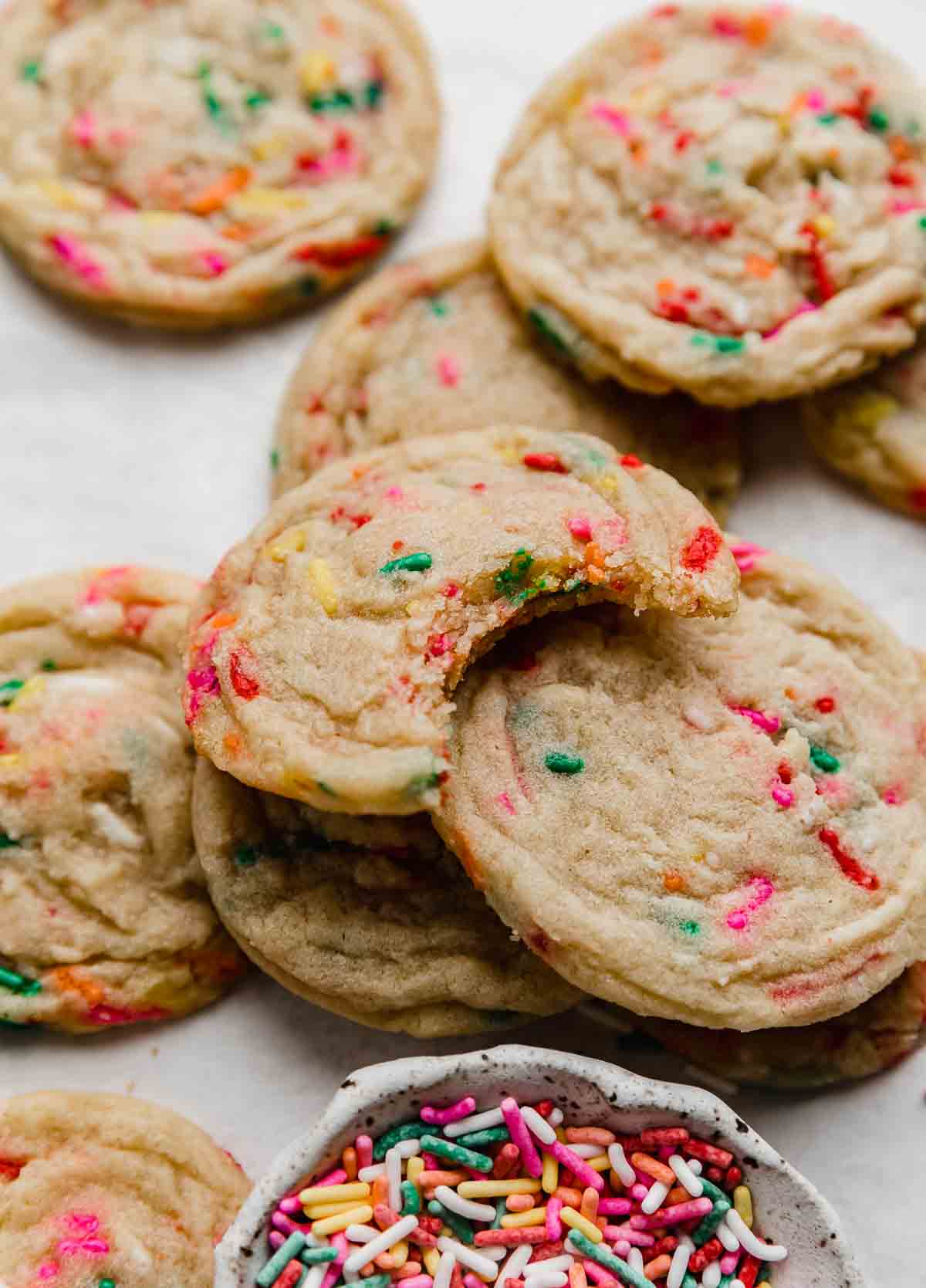 The best Funfetti Cookies on a white background with a bite taken out of one cookie.
