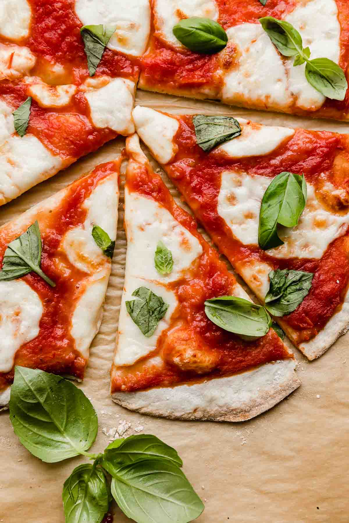 Several slices of Margherita Pizza with crushed tomatoes and fresh basil.