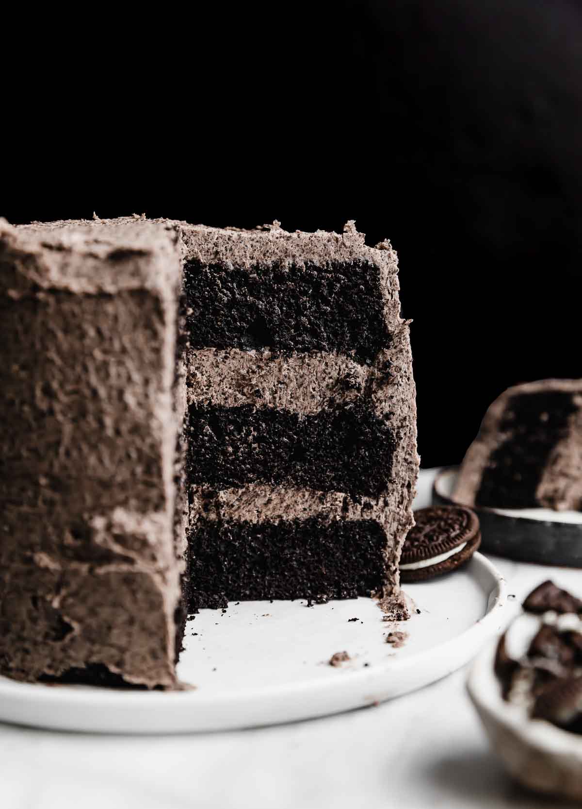 A three layer six inch Oreo Cake recipe topped with an Oreo frosting, against a black background.