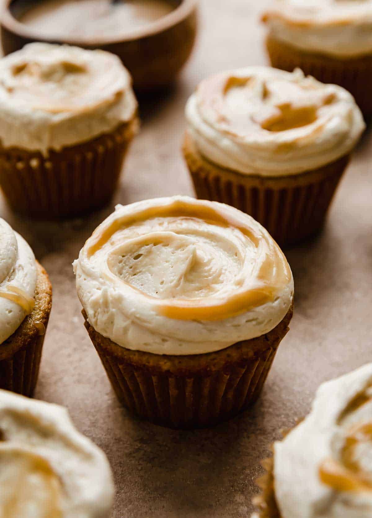 A Butterscotch frosting covered brown butter cupcake on a light brown background.