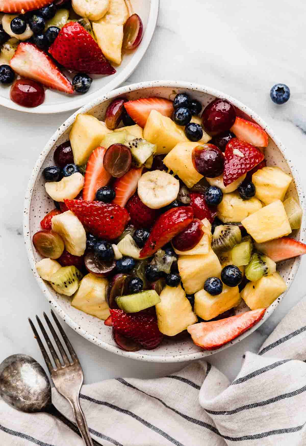 Fruit Salad cocktail with bananas, strawberries, blueberries, kiwi, pineapple topped with a honey dressing.