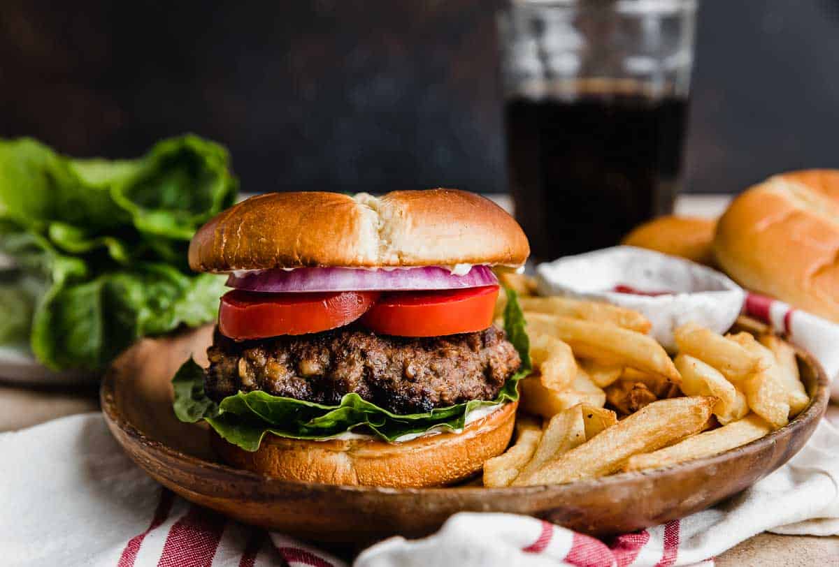 Steakhouse Burgers on a brown plate with French fries against a brown background.
