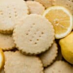 Round Lemon Shortbread Cookies surrounded by a sliced lemon.