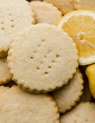 Round Lemon Shortbread Cookies surrounded by a sliced lemon.