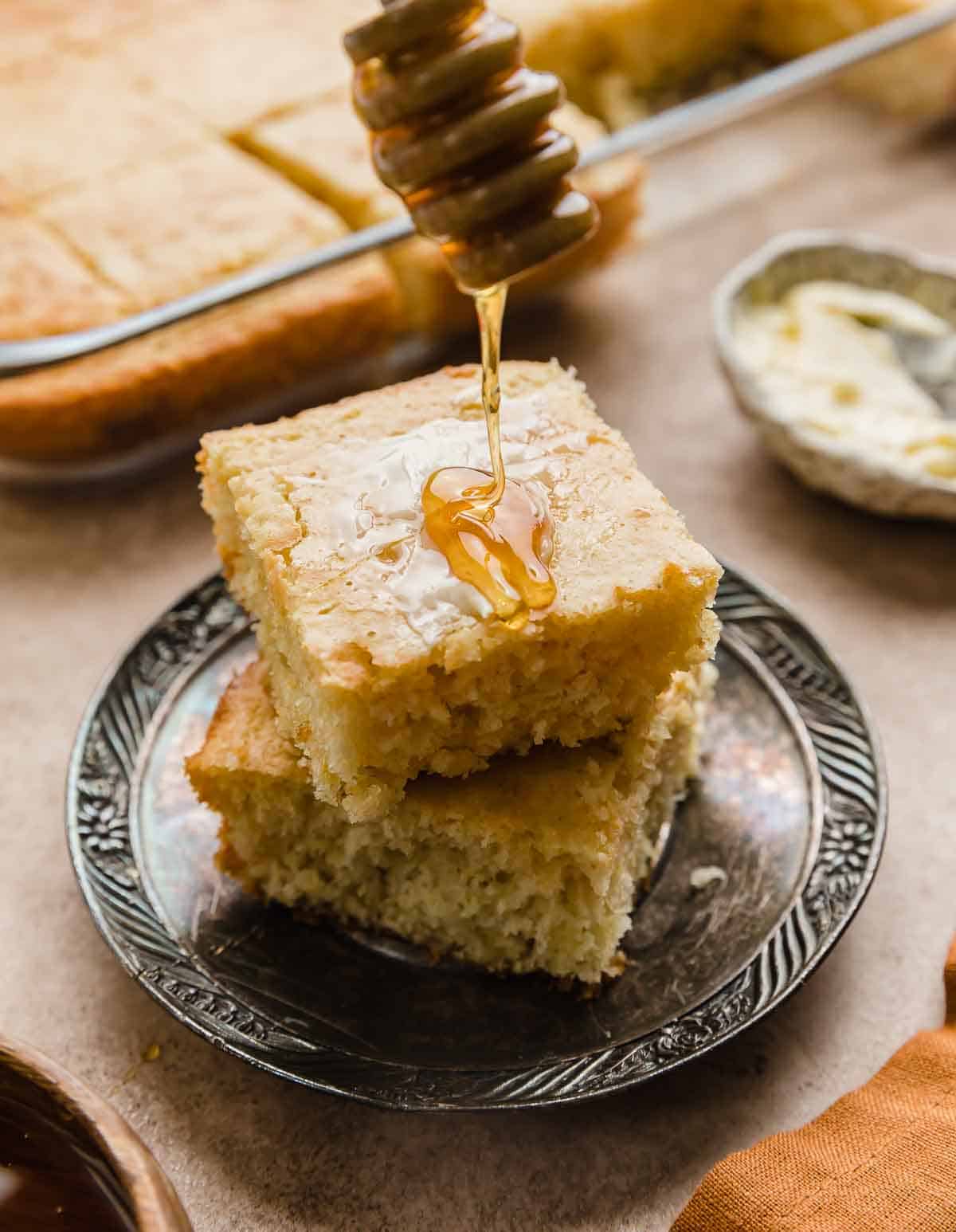 Honey being drizzled over a slice of homemade cornbread made with Bisquick.