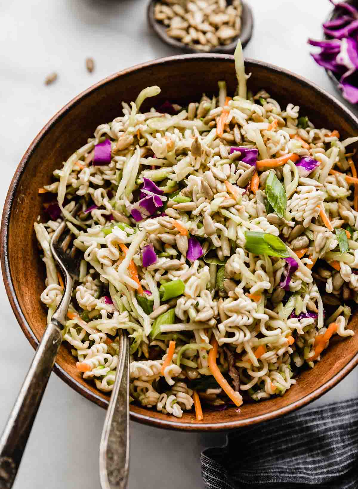 Asian Broccoli Slaw in a brown bowl with two forks to the left of the bowl.